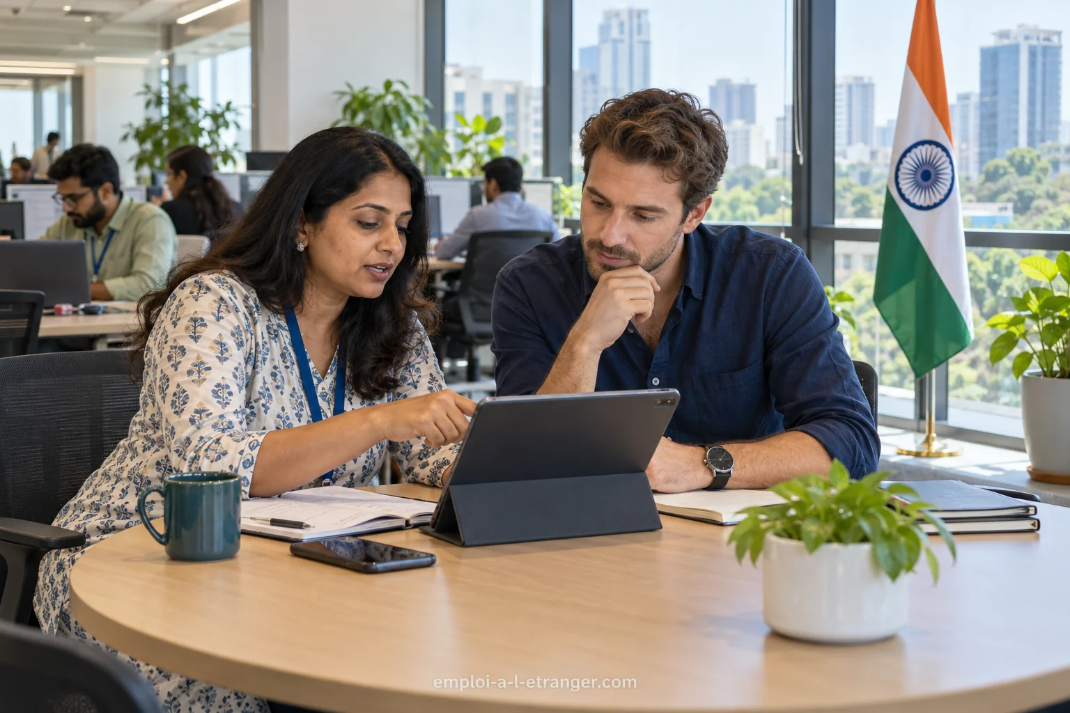 Ein Teamleiter und eine Kollegin betrachten in einem indischen Büro einen digitalen Dienst auf einem gemeinsamen Bildschirm